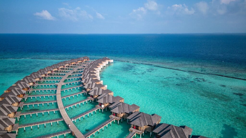 Maldives Island Overwater Villa Bungalows at turquoise hotel resort lagoon with aerial view