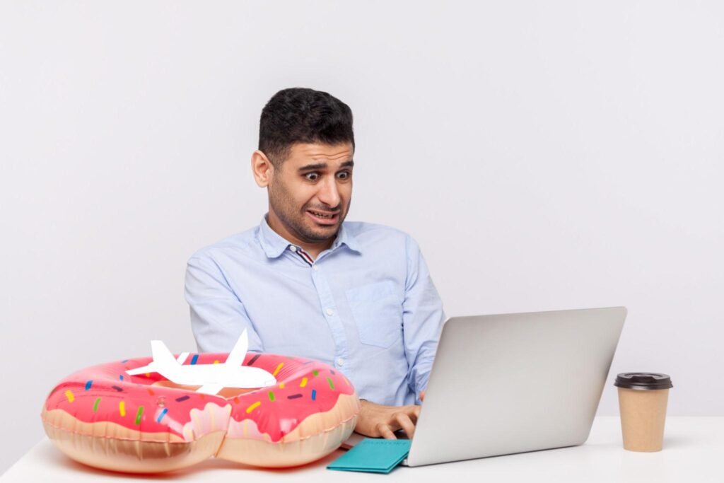 Man booking tickets or tour online using laptop, looking shocked surprised by price, searching low cost. isolated