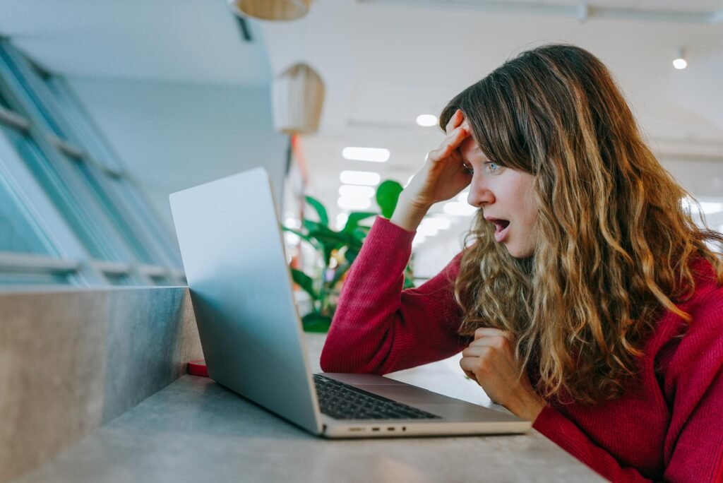 Frustrated traveler viewing expensive airline tickets on laptop screen, sitting in sleek airport terminal, experiencing financial stress during vacation planning