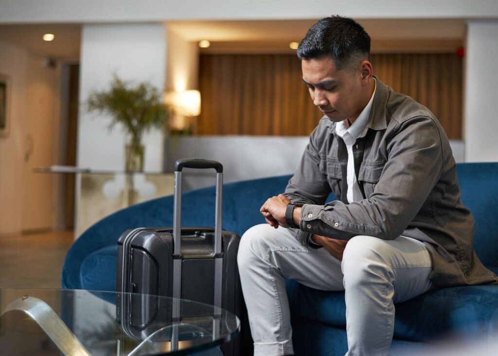 Traveler Waiting in Hotel Lobby with Luggage While Checking Time