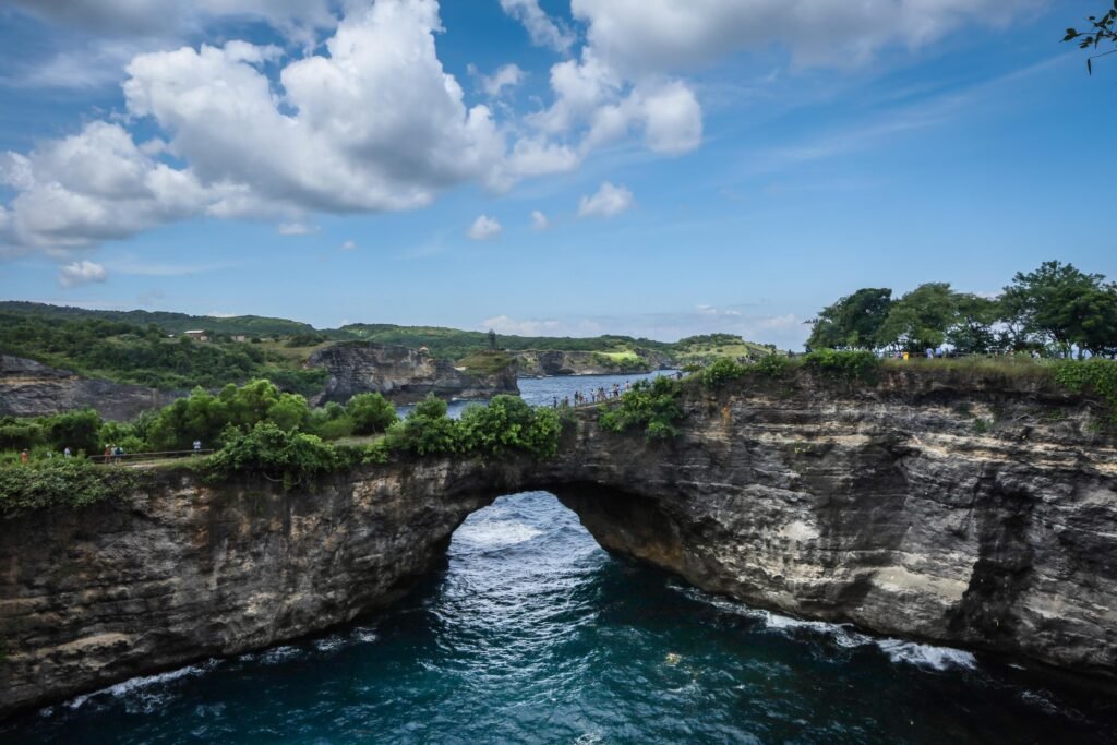 Stone arch and rocky cliffs at the Broken Beach viewpoint, Nusa Penida coast, Bali, Indonesia.