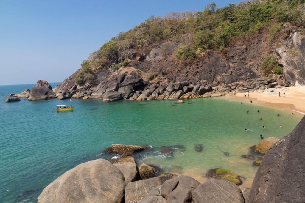 Beautiful secret beach Butterfly in Goa, India. Aerial view of pristine beach with rocky bay and waves crashing