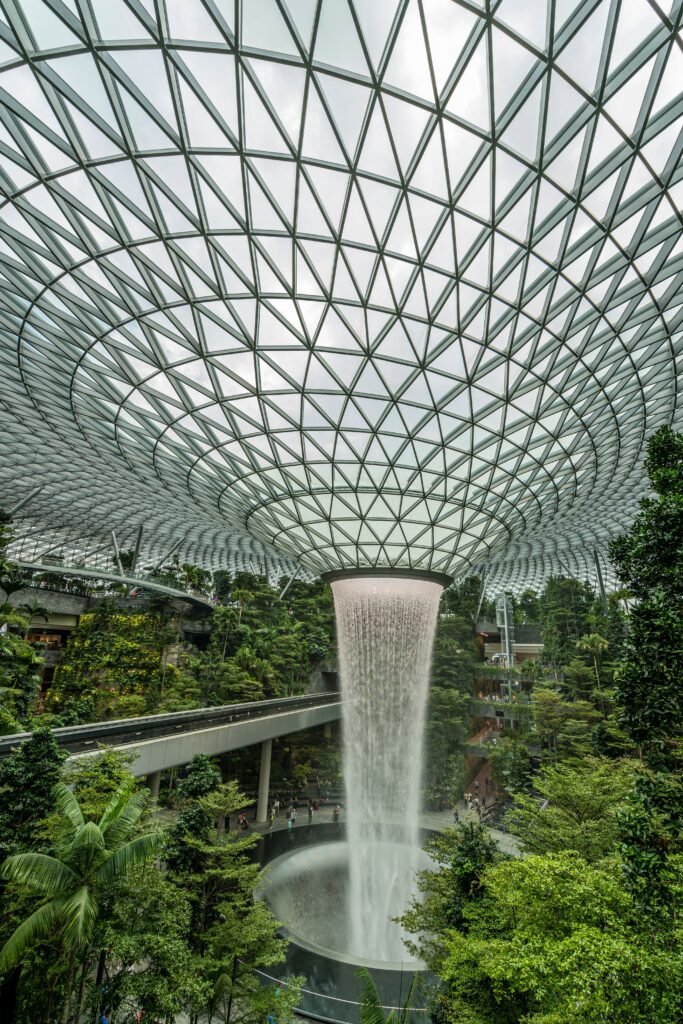 Stunning indoor waterfall surrounded by lush greenery and modern architecture at Singapore's Jewel Changi Airport.