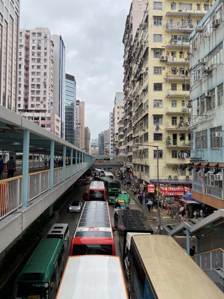 A bustling city scene with traffic and pedestrians on a cloudy day.