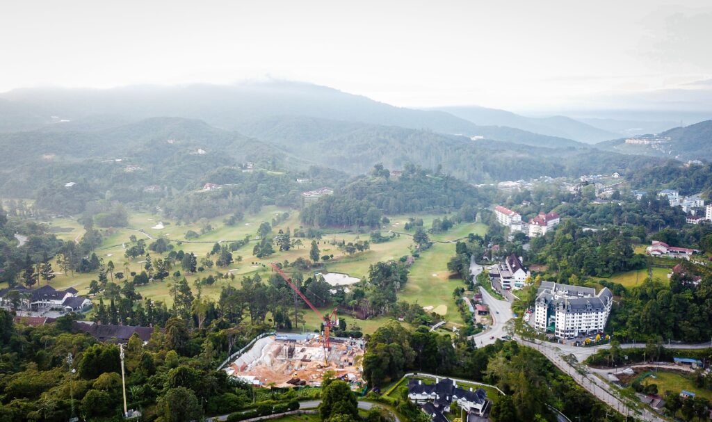 Scenic aerial shot of a town surrounded by misty mountains, forests, and construction site.