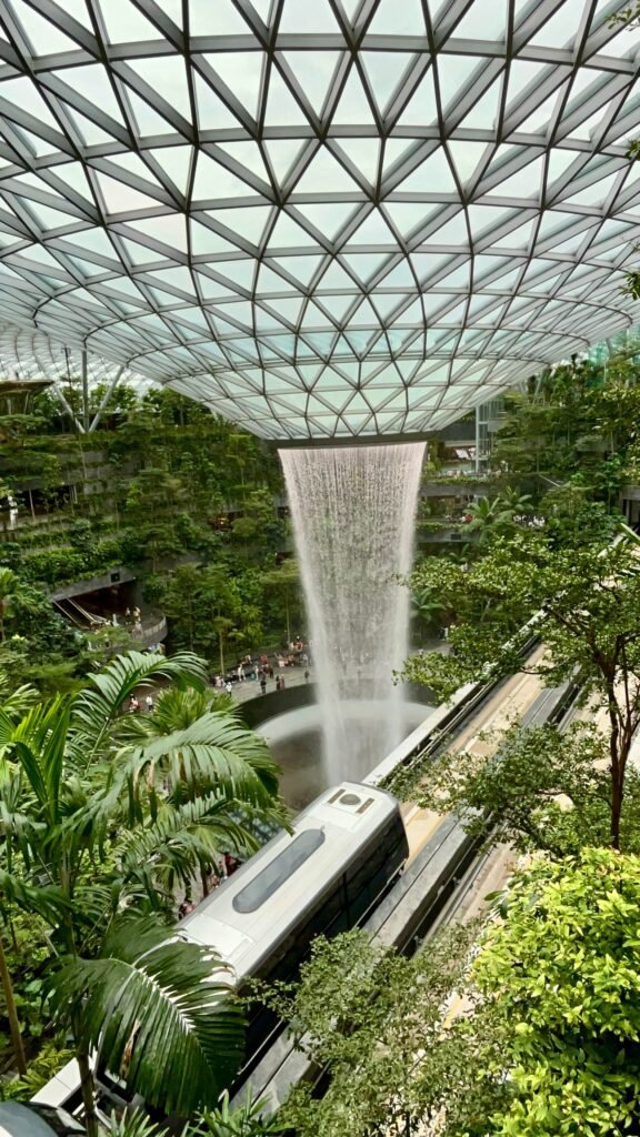 Spectacular indoor waterfall at Changi Airport's Jewel, Singapore, surrounded by lush greenery.