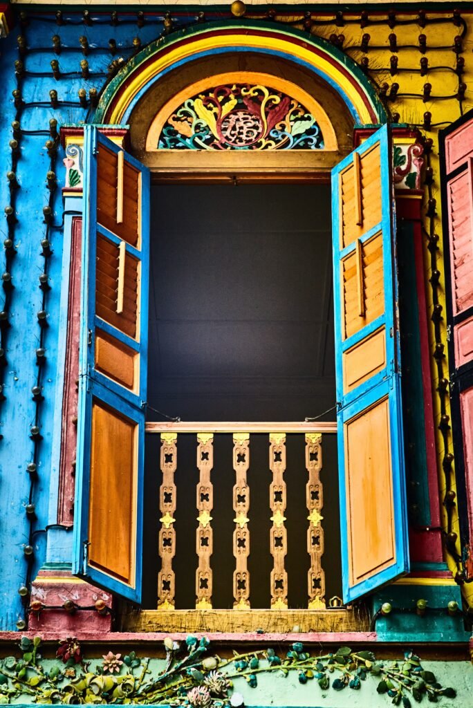Colorful traditional window with intricate wooden carvings and open shutters.
