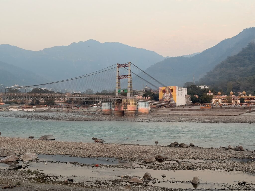 Laxman Jhula bridge spanning Ganges River in Rishikesh with mountainous backdrop.