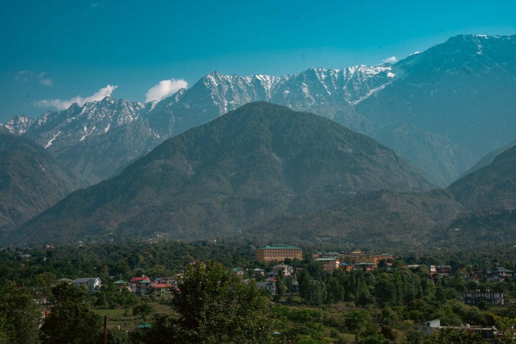 Breathtaking mountain range with valley and cityscape under clear blue sky.