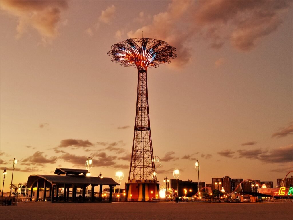 Coney Island's Parachute Jump Tower illuminates the evening sky at sunset, offering a nostalgic view of the iconic landmark.