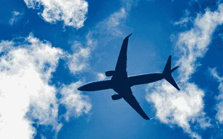 Commercial airplane flying through a blue sky with white clouds during daytime