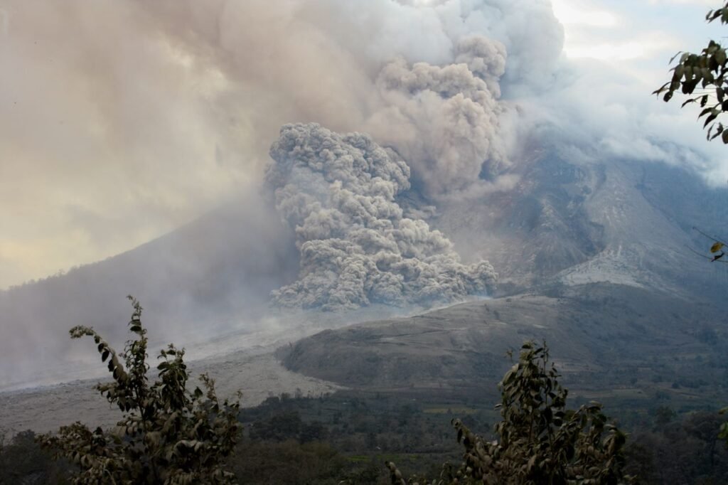 A powerful eruption of Mount Sinabung in North Sumatra, Indonesia, showcasing volcanic smoke and ash clouds.