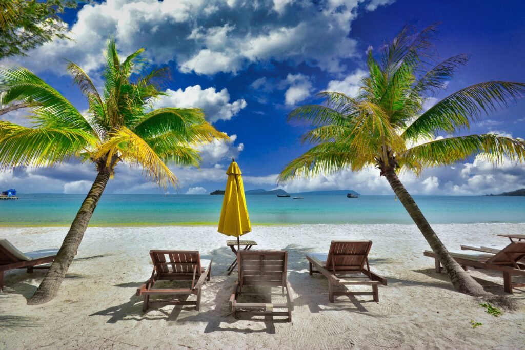 Peaceful tropical beach with palm trees and lounge chairs in Koh Rong, Cambodia.