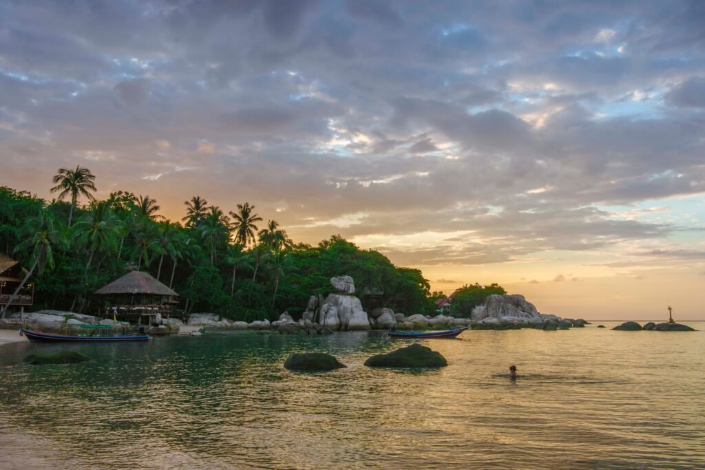 Peaceful sunset scenery at Ko Tao beach in Thailand featuring rocky shoreline and tranquil waters.