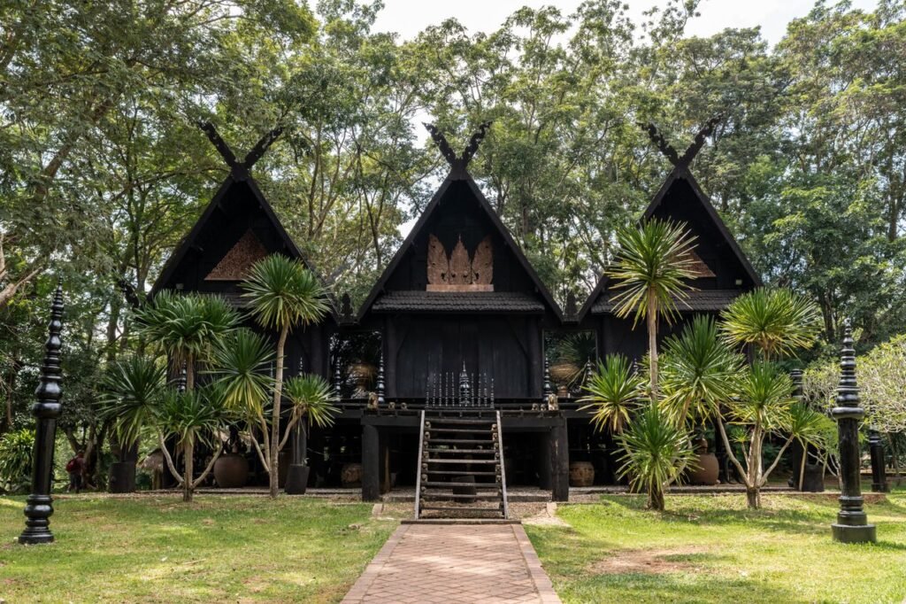 Traditional Thai structure amidst lush greenery, showcasing unique architecture in Chiang Rai, Thailand.