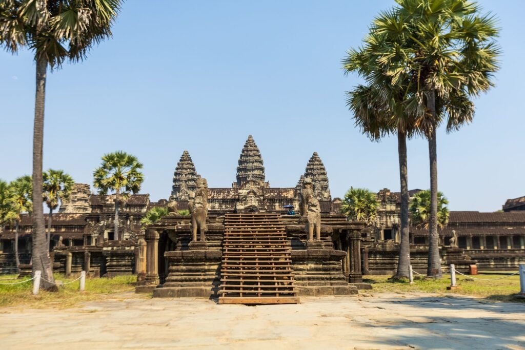 Majestic view of Angkor Wat temple entrance surrounded by palm trees in Cambodia.
