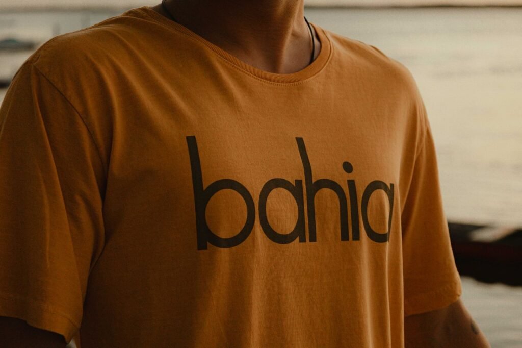 Close-up of a man wearing a Bahia-themed t-shirt outdoors during sunset.