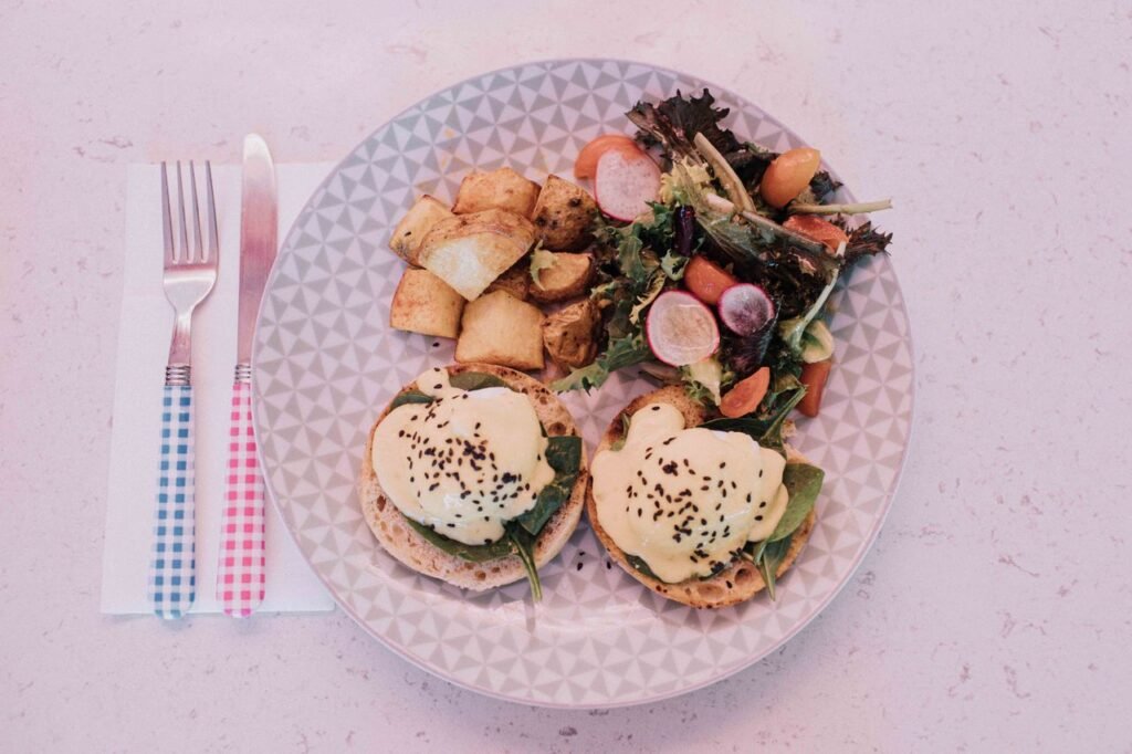 Tasty eggs benedict served with salad and potatoes, perfect for brunch.