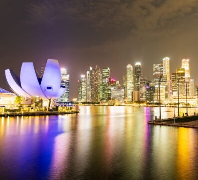 Night view of Singapore's illuminated skyline and Marina Bay Sands, reflecting vibrant city lights.