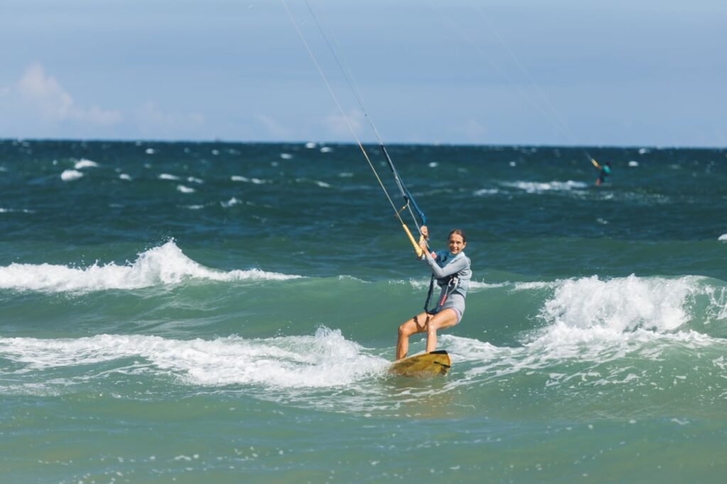 A woman enjoying an adventurous kiteboarding experience on the ocean waves during a sunny summer day.
