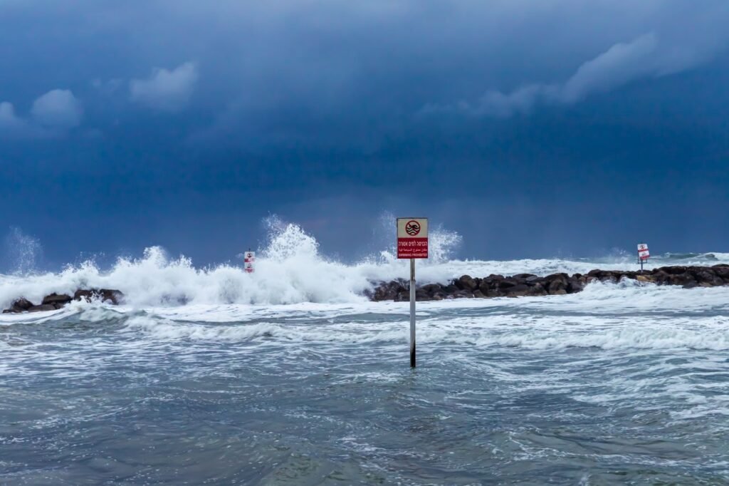 Dramatic sea waves splashing against rocks under a stormy sky in Tel Aviv, Israel.