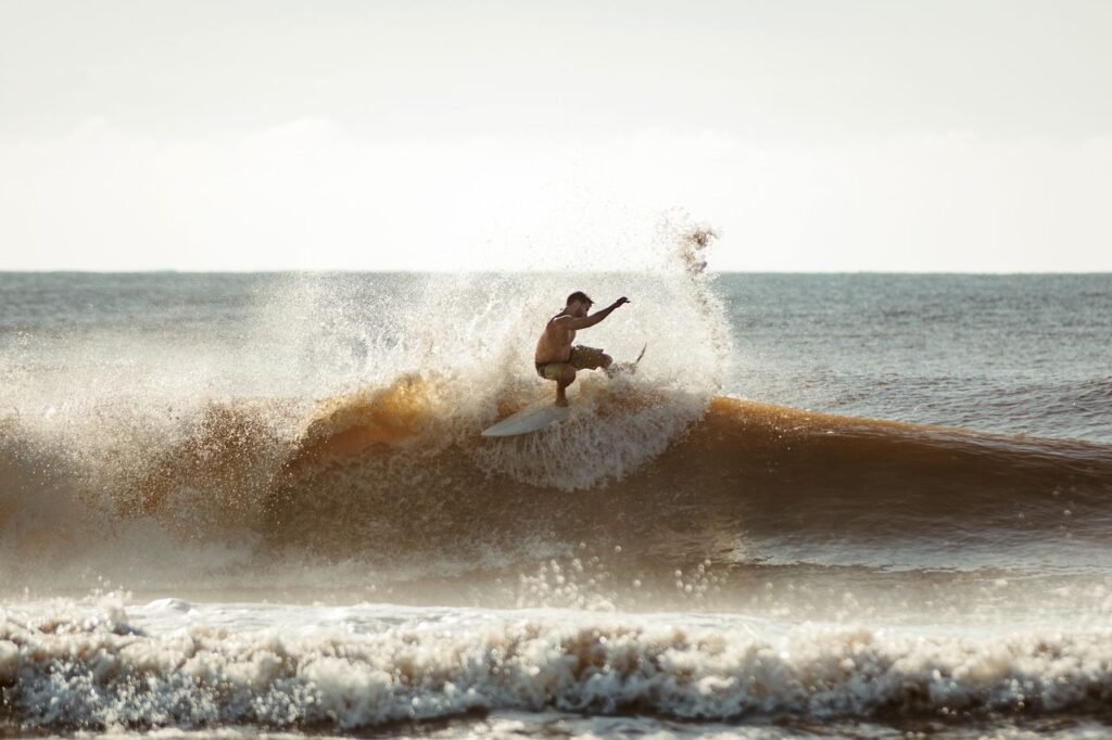 A dynamic action shot of a surfer catching a wave under a clear sky.
