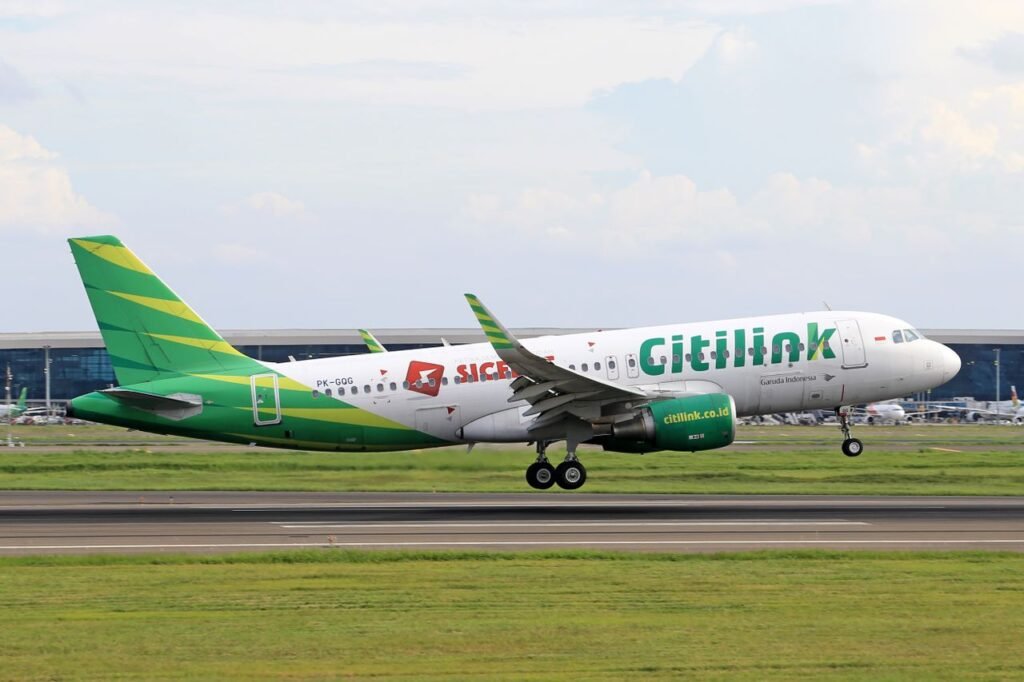 Citilink aircraft landing on a runway with terminal in the background, showcasing air travel and transportation.