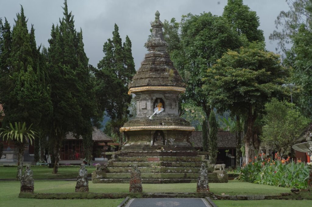 A serene ancient Balinese temple with a prominent Buddha statue in a lush garden setting, symbolizing spirituality and peace.