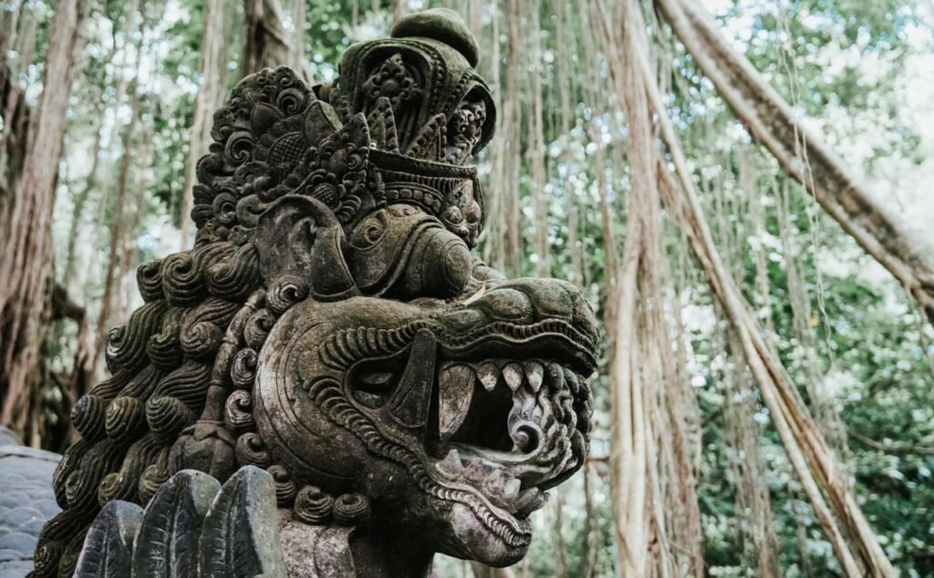 A detailed Balinese stone sculpture depicting a mythological creature amidst lush jungle backdrop.