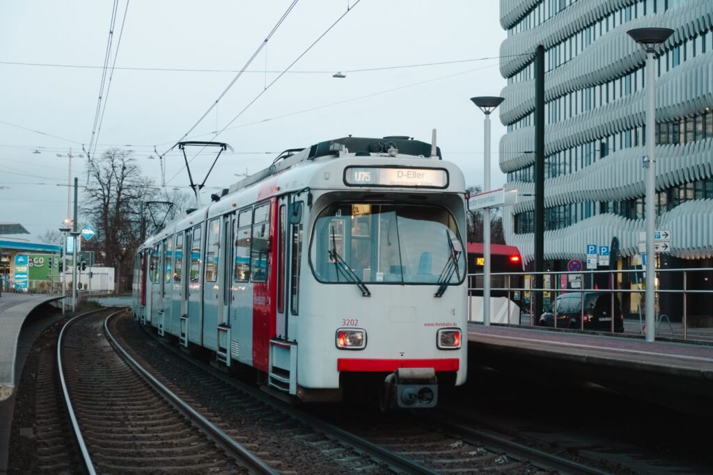A modern tram at a station in Düsseldorf, showcasing urban transportation and architecture.
