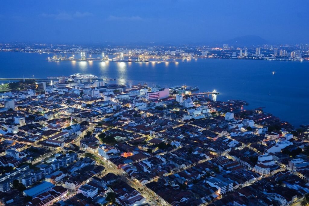 Captivating night aerial skyline of Penang, Malaysia, showcasing urban lights and sea view.