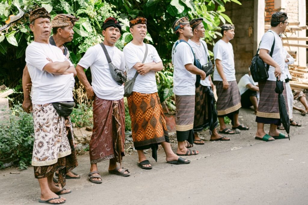 Group of Balinese men wearing traditional clothing, standing outdoors during a cultural gathering.