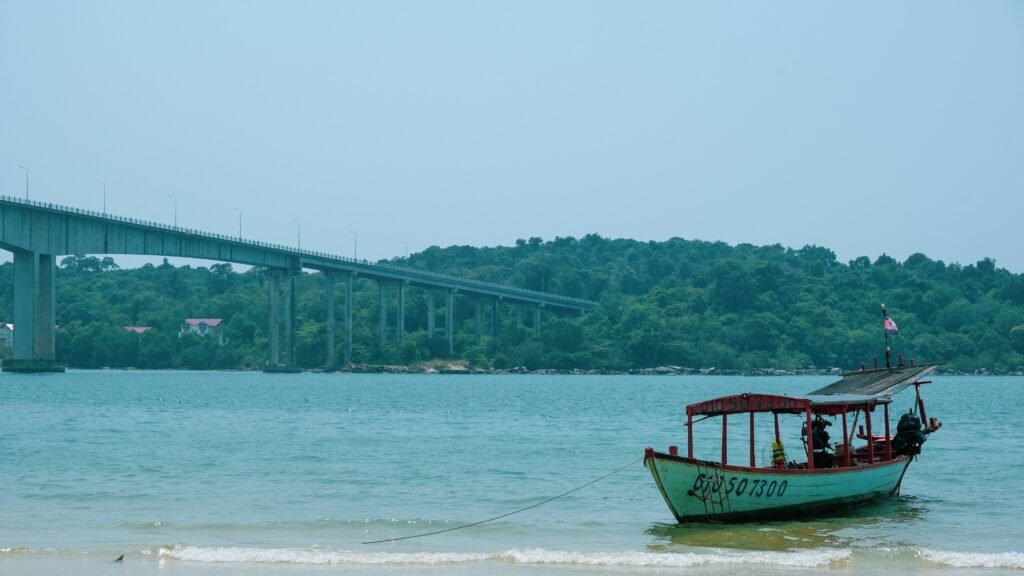 Peaceful seaside scene with a boat and bridge in Sihanoukville, Cambodia.
