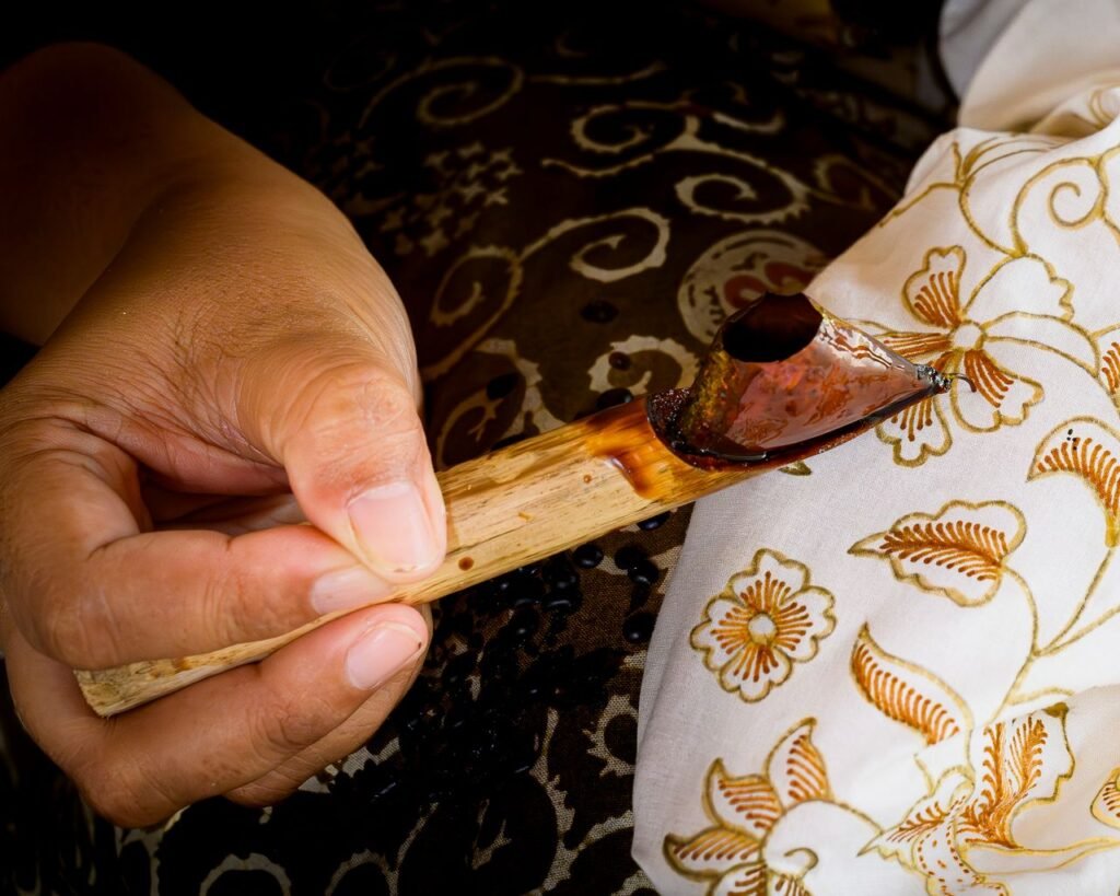Close-up of a hand crafting traditional batik with hot wax in Jakarta, Indonesia.