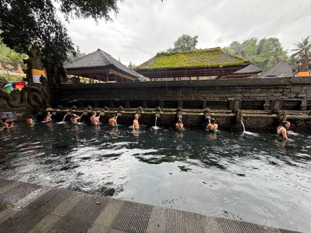 Tourists enjoy a traditional holy bathing ritual at Tirta Empul Temple, Bali.