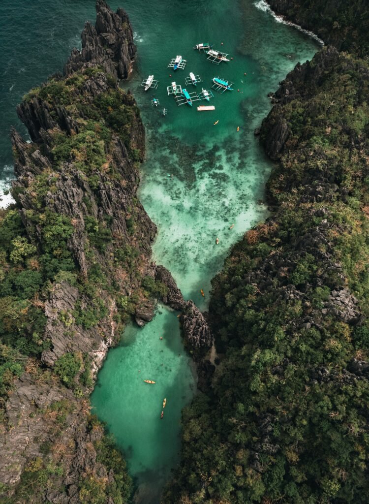 Stunning aerial view of boats in a turquoise lagoon surrounded by cliffs in El Nido, Philippines.