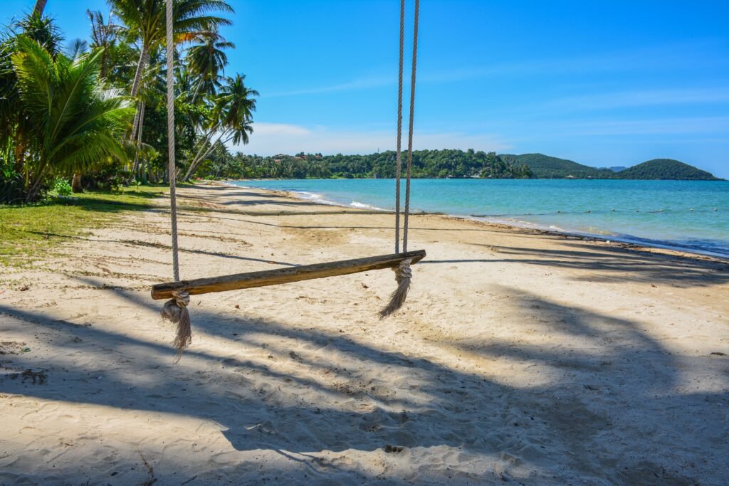Enjoy a serene view of a sandy beach with a swing on Ko Mak, Thailand, under clear blue skies.