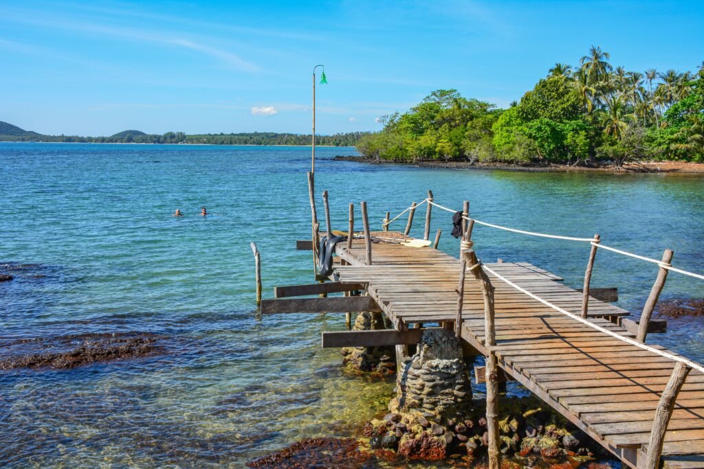 Tranquil seaside scene with a rustic pier on Ko Mak, Thailand, under a bright summer sky.