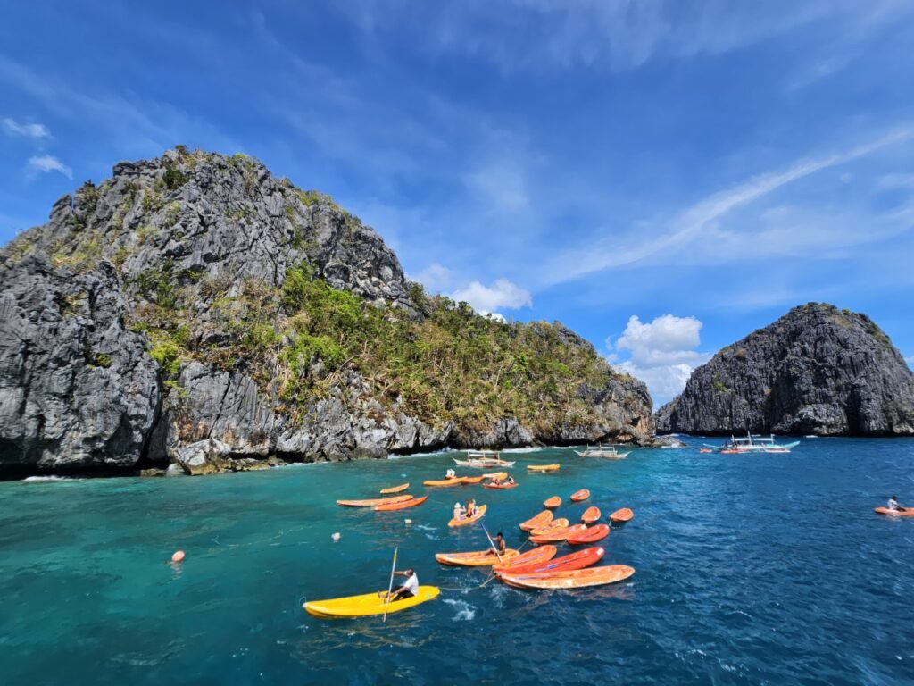 A vibrant scene of kayakers exploring the limestone cliffs in El Nido, Philippines.