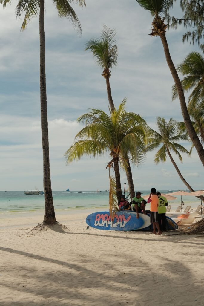 Palm trees and sandy beach with people in Boracay, Philippines.