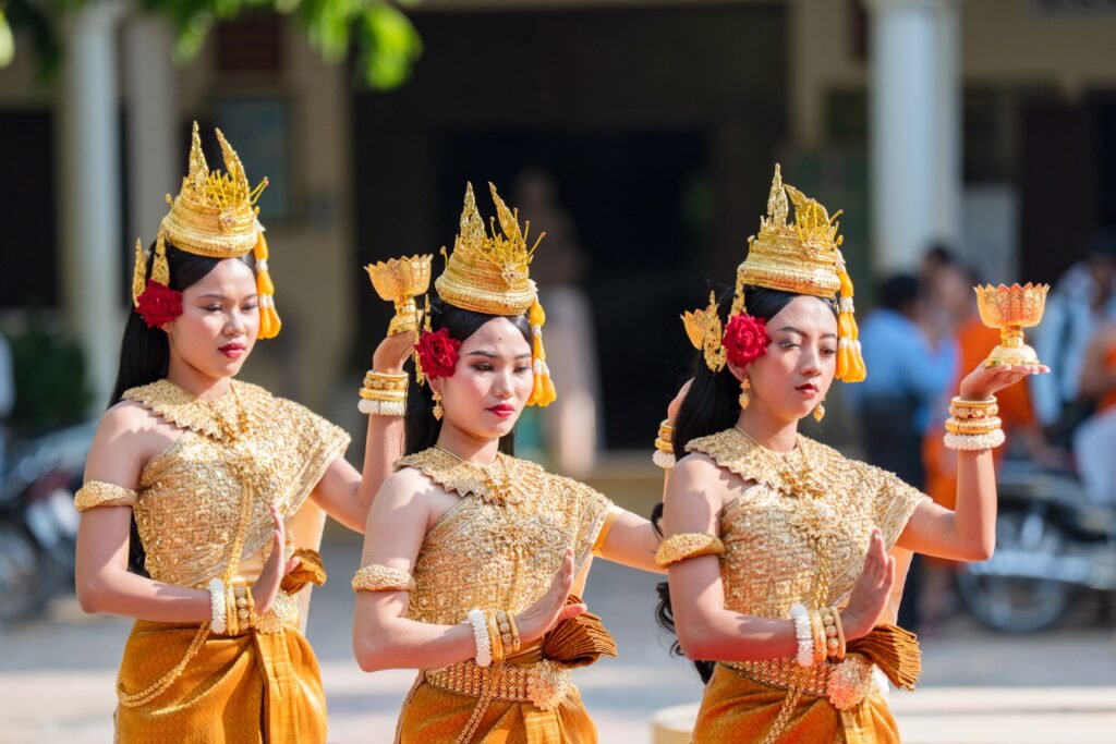 Three female dancers in traditional Khmer attire performing a cultural ceremony.