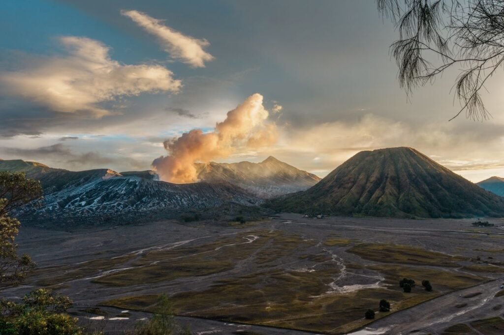 A breathtaking view of Mount Bromo in East Java, Indonesia, with erupting smoke at sunrise.