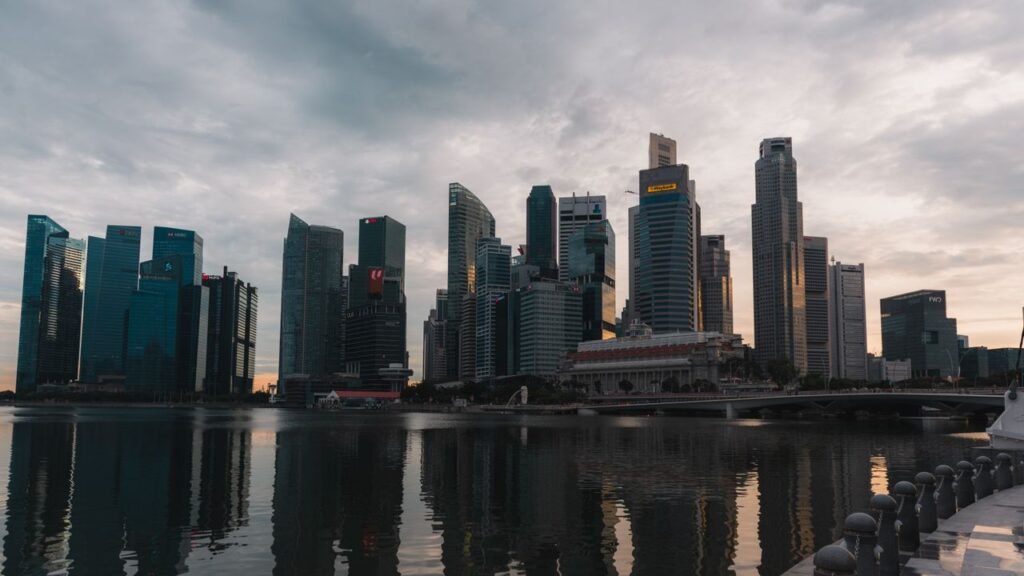 Dramatic skyline of Singapore reflecting on waterfront at dusk with towering skyscrapers.