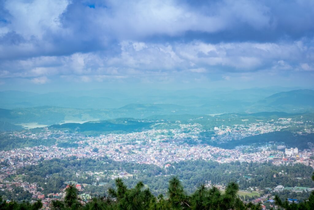 Breathtaking aerial view of a vibrant town in West Khasi Hills, India surrounded by lush greenery and mountains under a vivid sky.