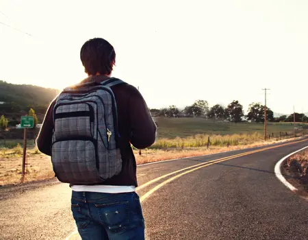 Backpacker walking along a scenic country road during a solo travel adventure