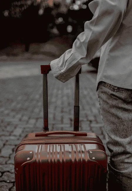 Traveler pulling a wheeled suitcase while walking outdoors