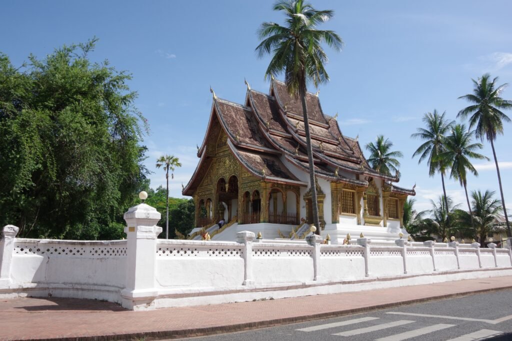 Explore the Royal Palace's intricate architecture surrounded by lush palms in Luang Prabang, Laos.