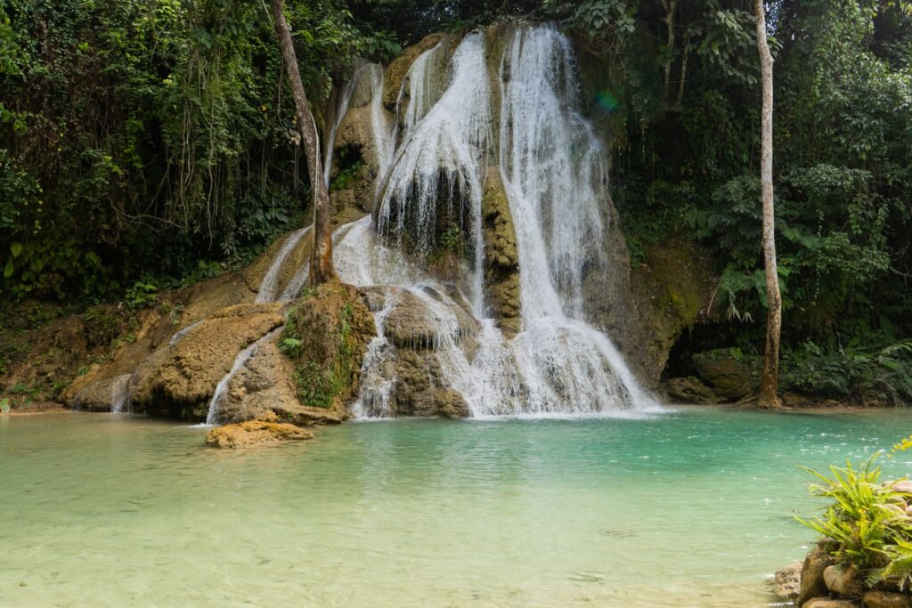 Discover the tranquil beauty of a waterfall surrounded by lush greenery in Luang Prabang, Laos.