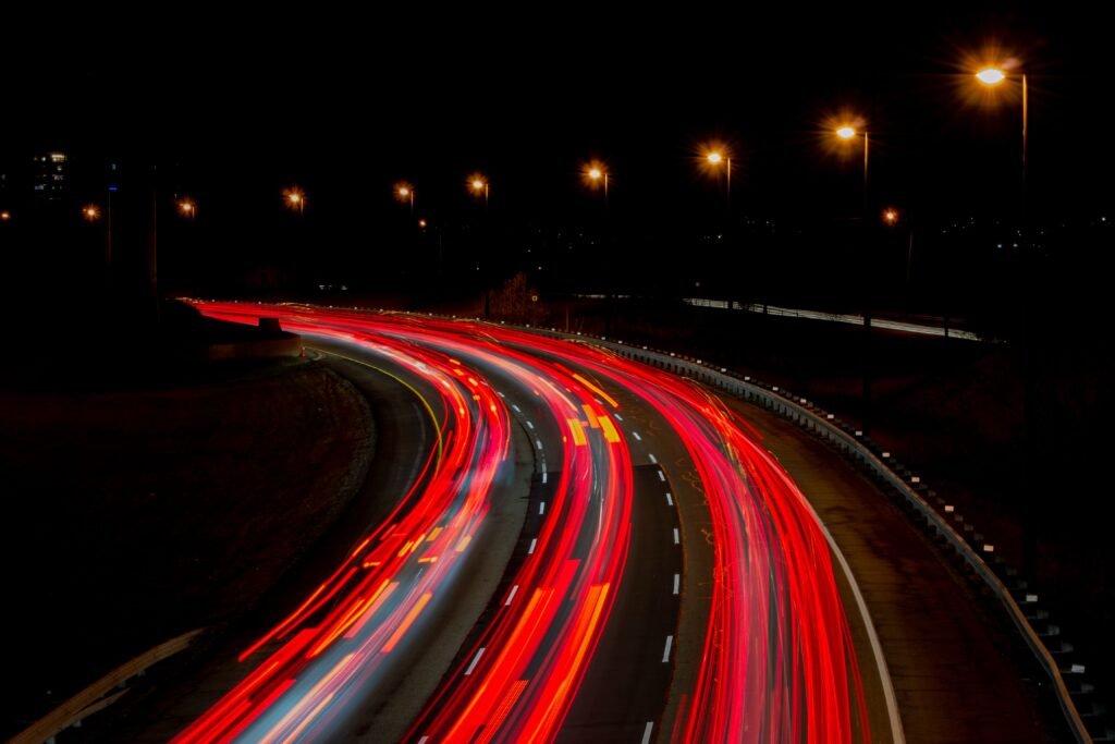 A captivating long exposure of a highway at night, showcasing vibrant light trails under streetlamps.