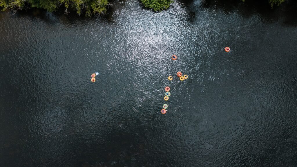 Aerial shot of people relaxing in tubes on a serene river during summer.
